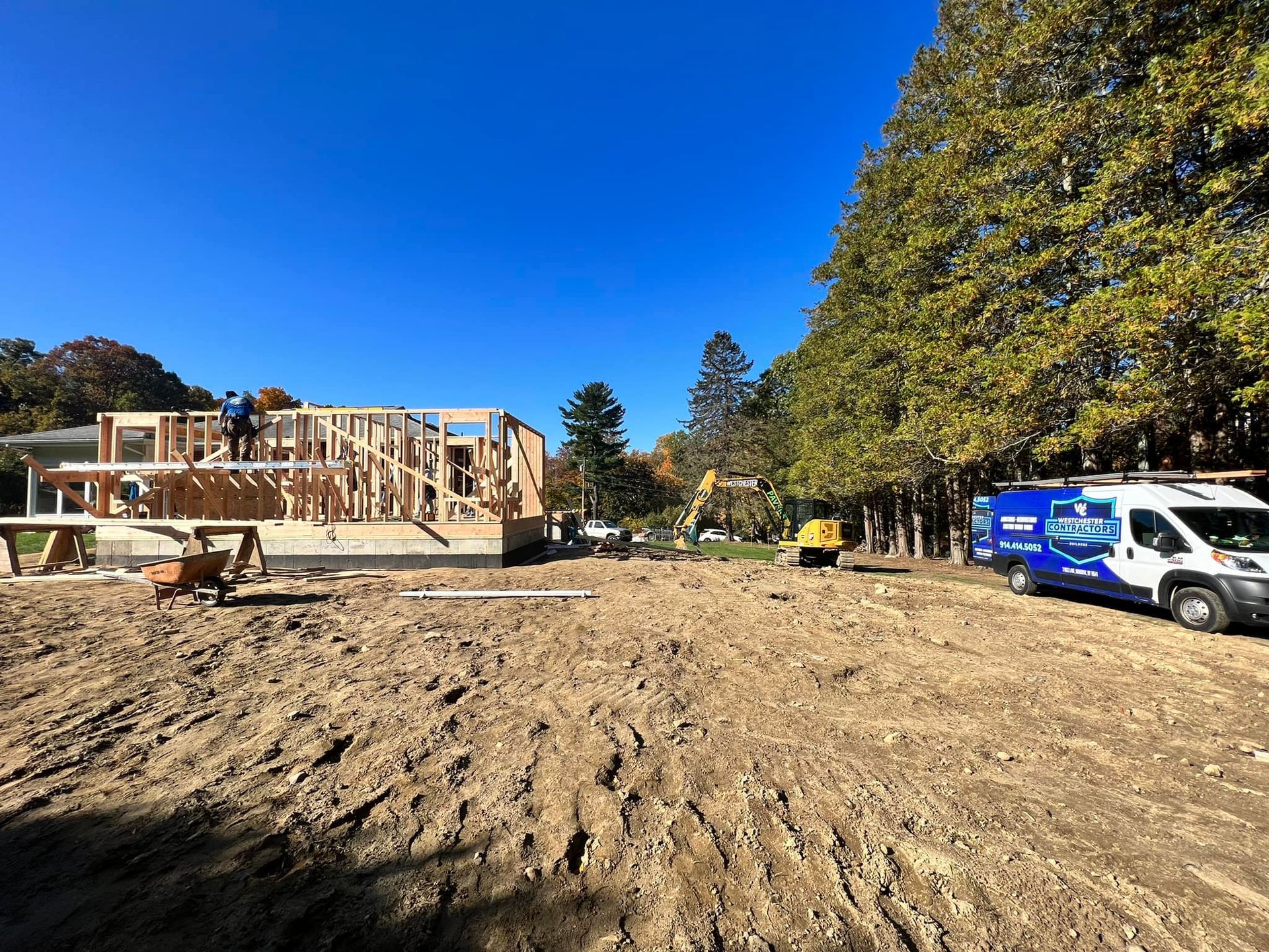 A construction site with a blue van parked in the dirt.