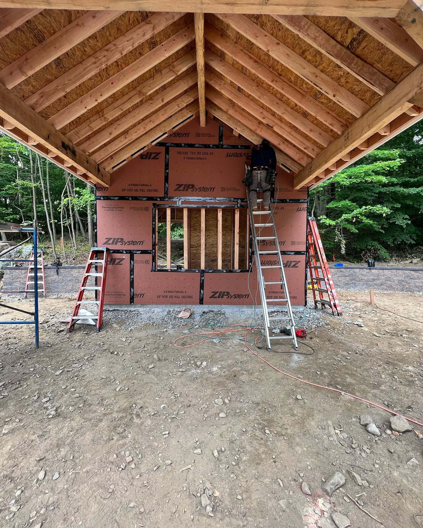 A man is standing on a ladder in front of a building under construction.