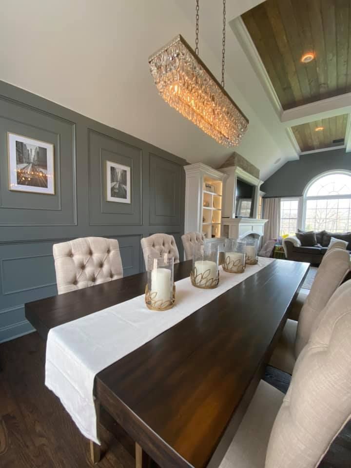 A dining room table with candles on it and a chandelier hanging from the ceiling.