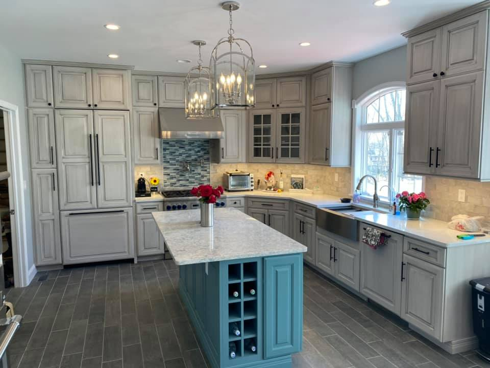 A kitchen with gray cabinets and a blue island.