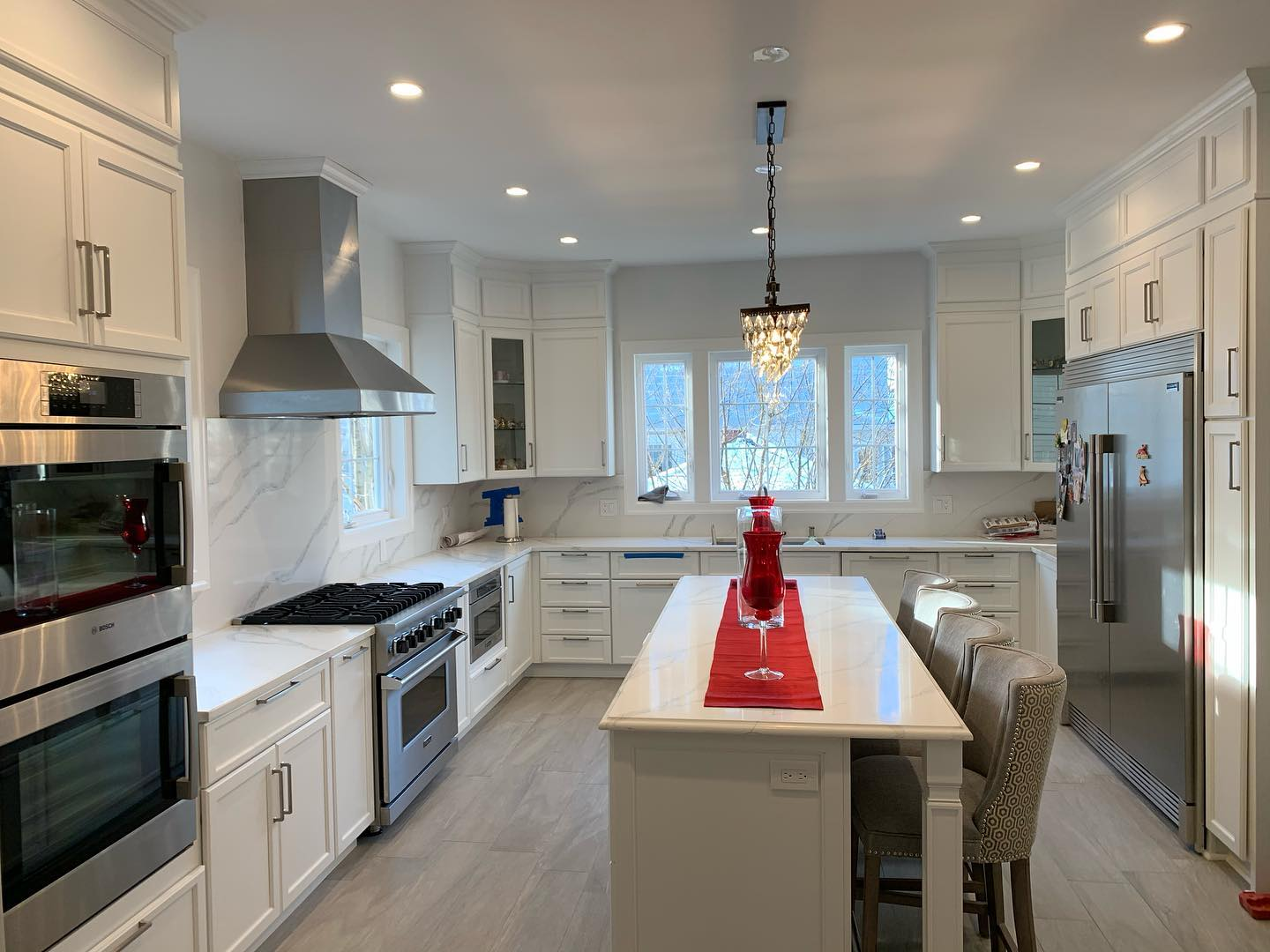 A kitchen with white cabinets and stainless steel appliances and a large island.