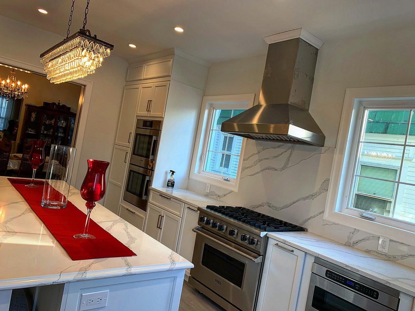 A kitchen with white cabinets , stainless steel appliances , a stove , and a large island.