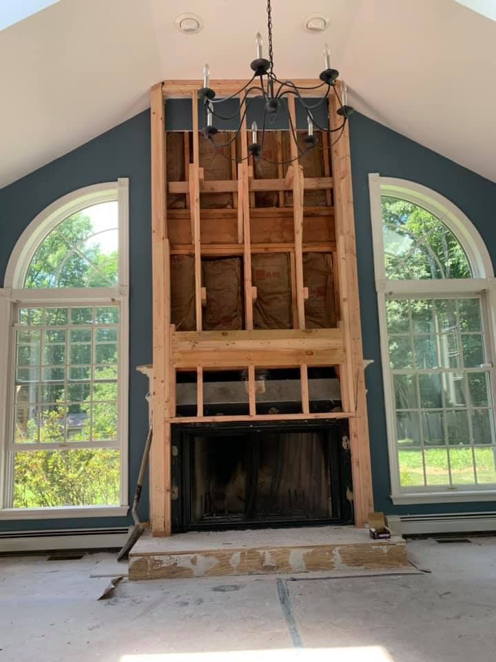 A large fireplace is being remodeled in a living room.