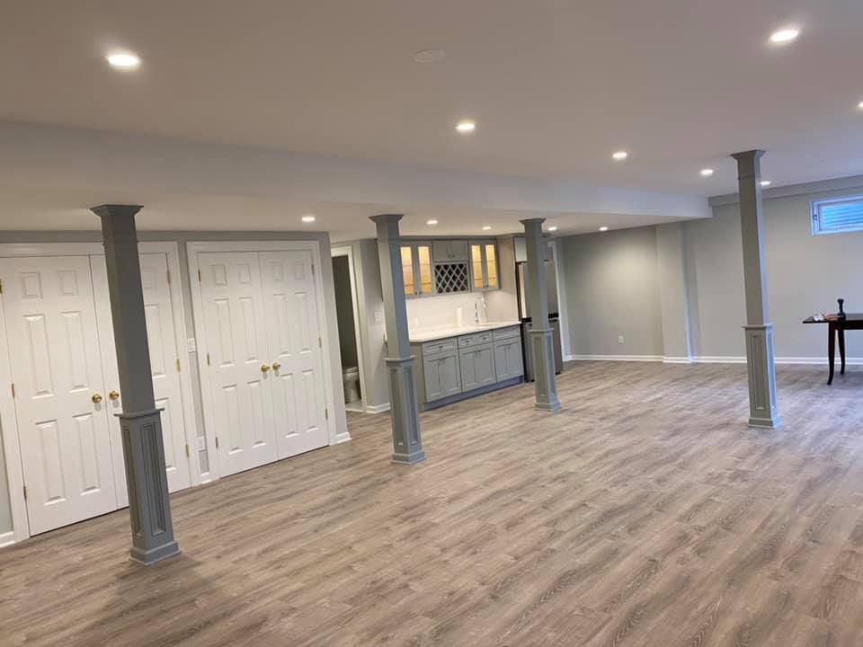 A large empty basement with hardwood floors and columns.