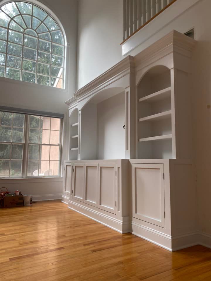An empty living room with white cabinets and a large window