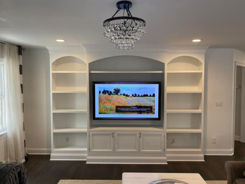 A living room with a tv on the wall and shelves.