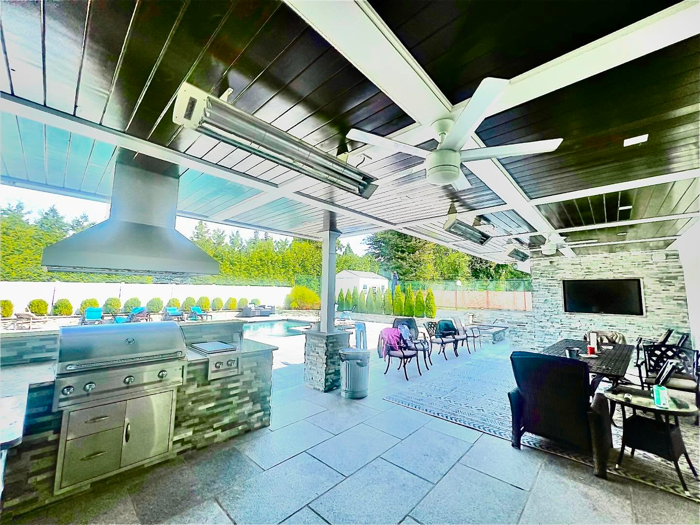 A large covered patio with a grill and a television.
