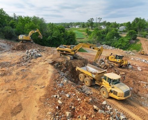Construction site: excavators, dump truck, and bulldozer moving dirt and rocks.