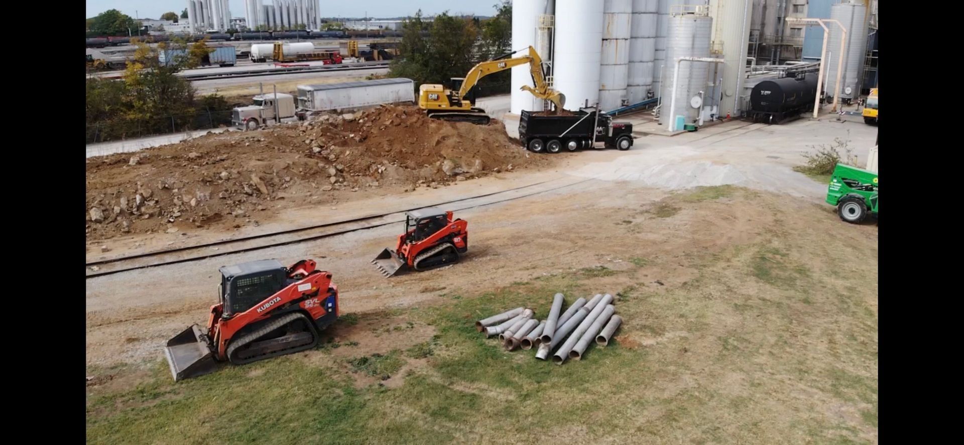 Construction site with excavators, trucks, and skid steers.