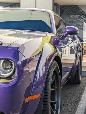A purple dodge challenger is parked in a parking lot.