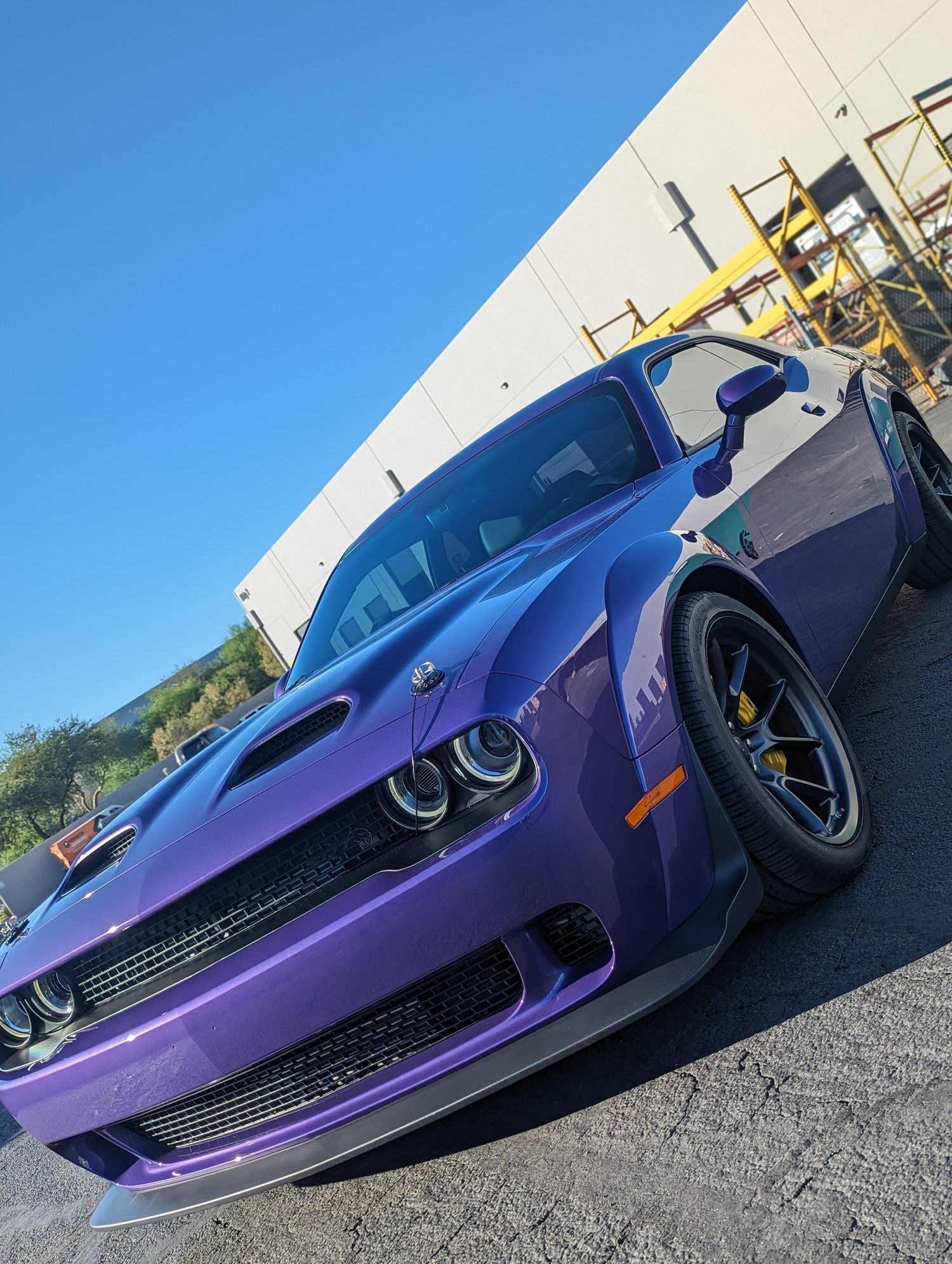 A purple dodge challenger is parked in front of a building.
