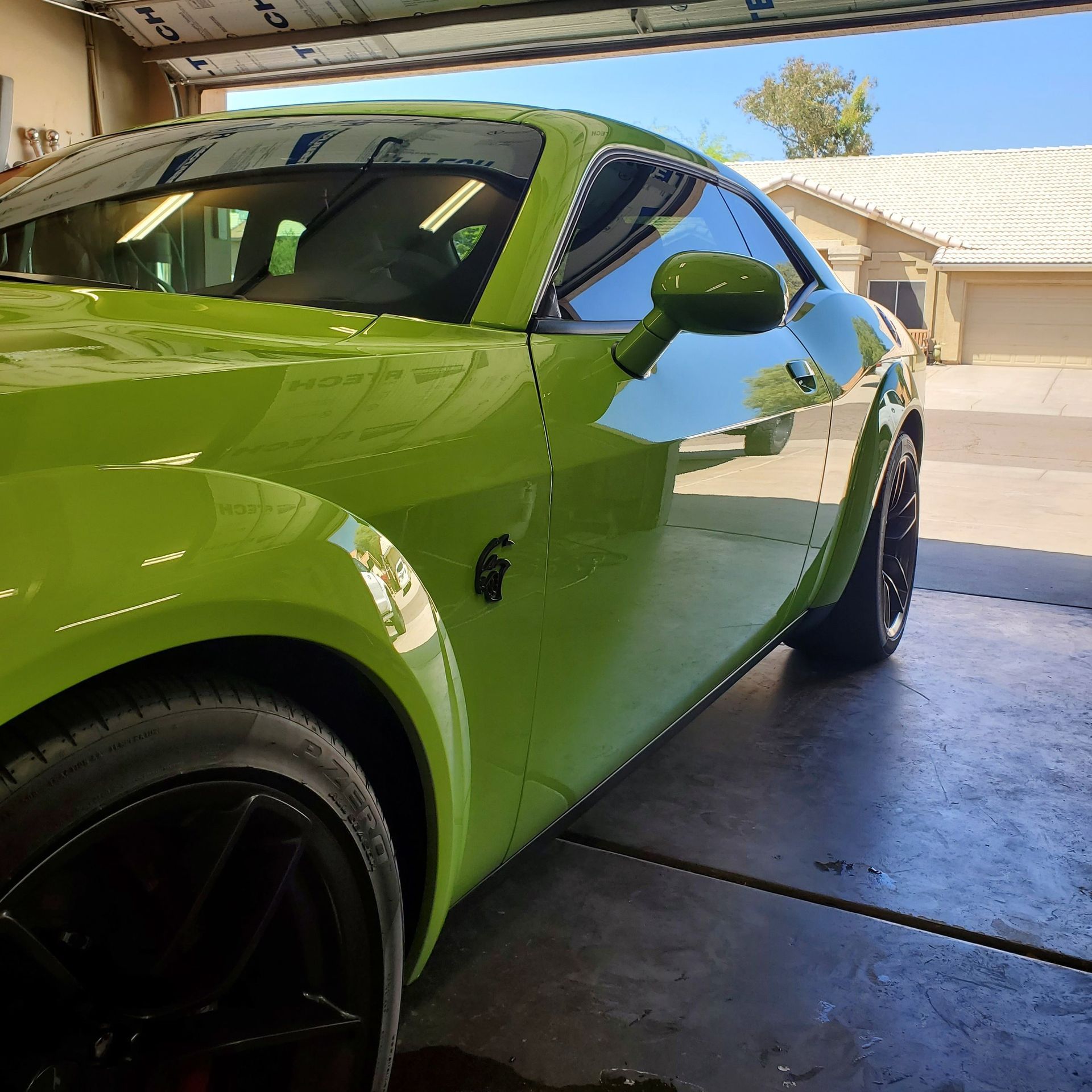 A green sports car is parked in a garage