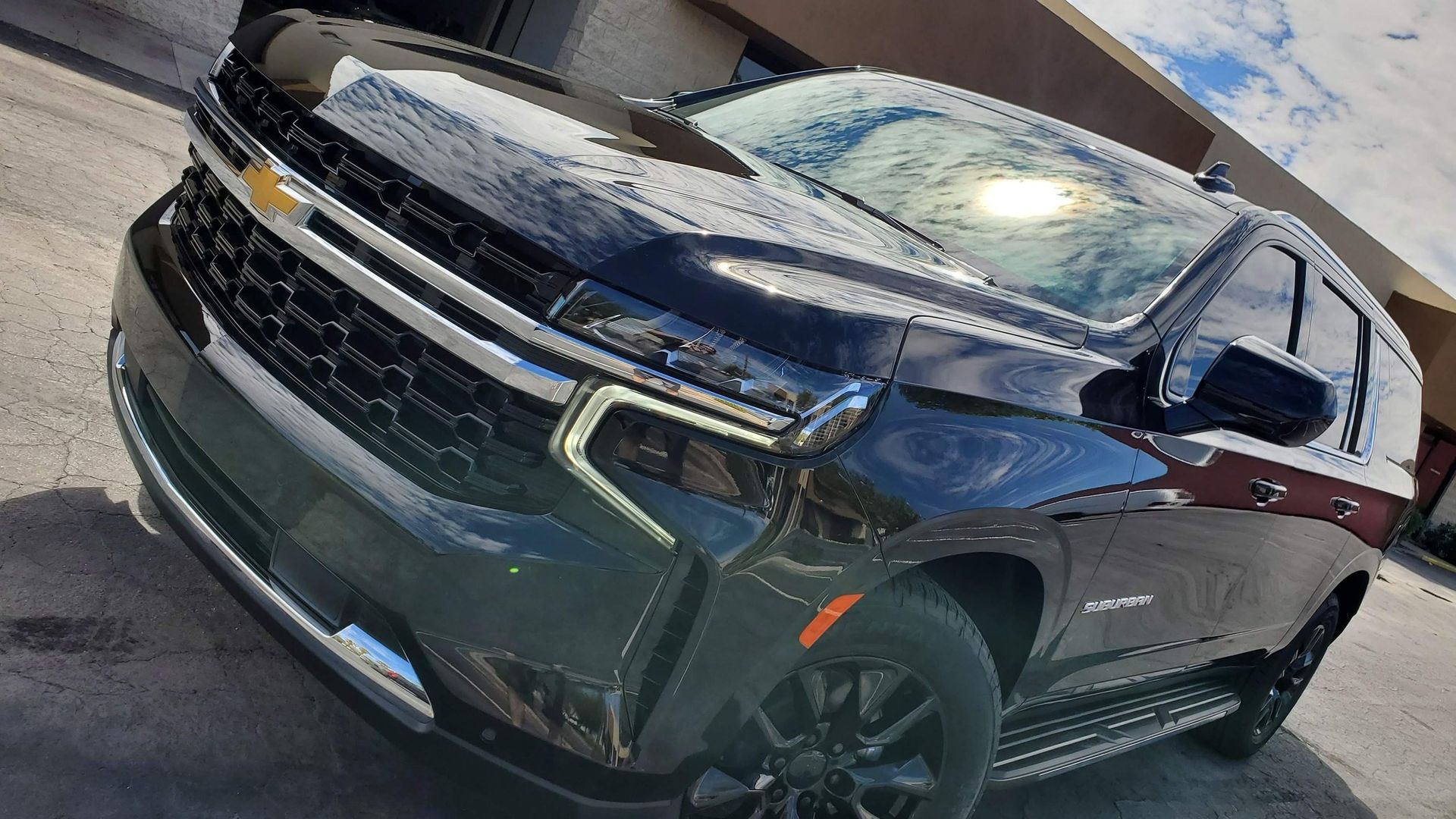 A black suv is parked in front of a building.