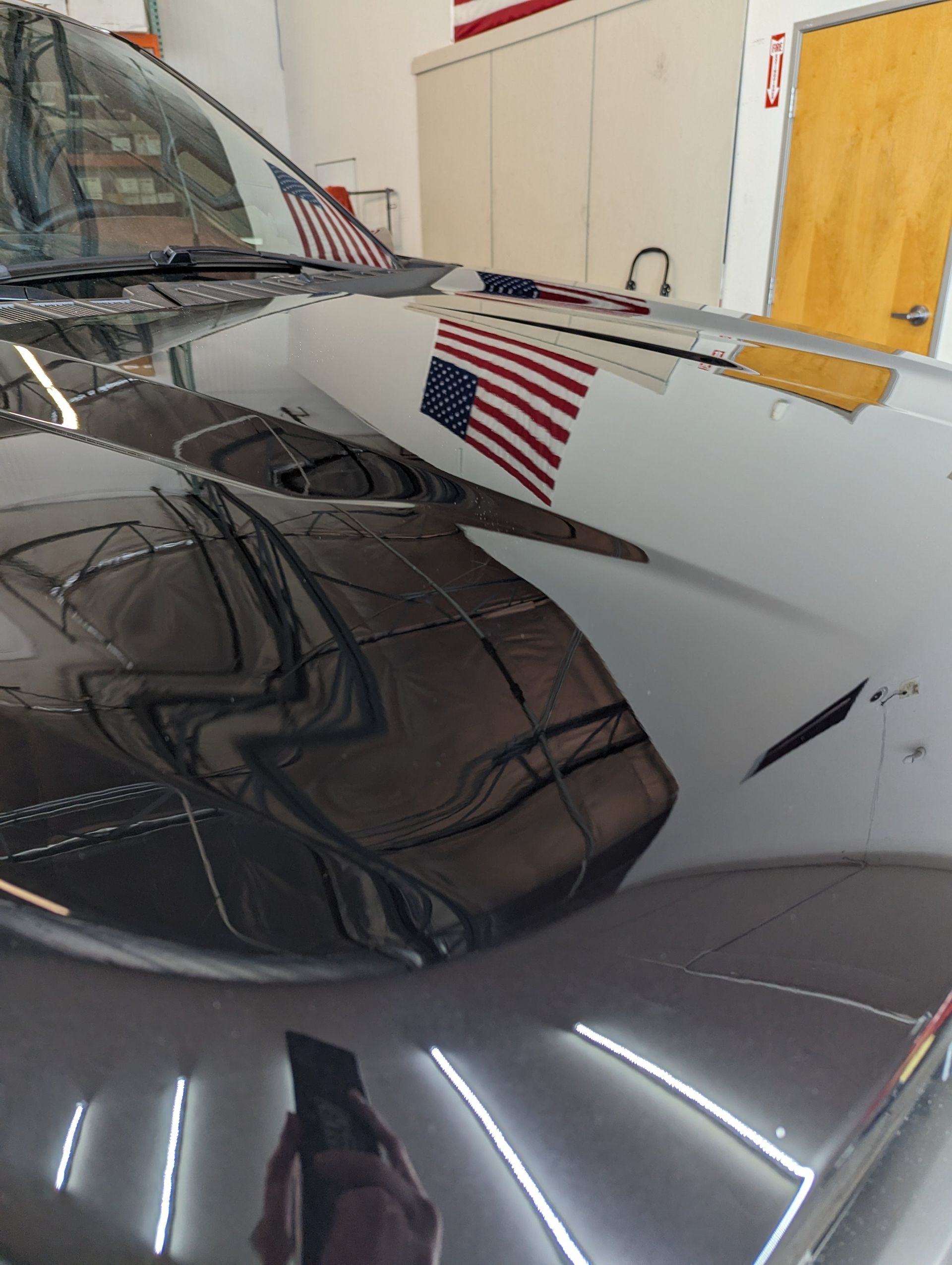 A black car with an american flag reflected in the hood