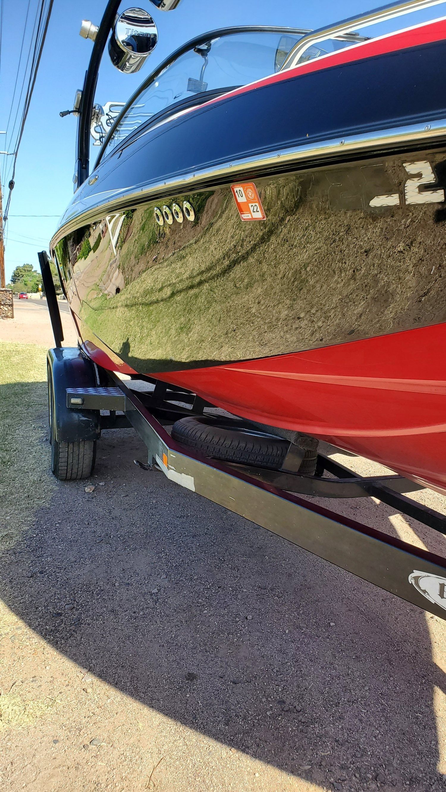 A red and blue boat is parked on a gravel road.