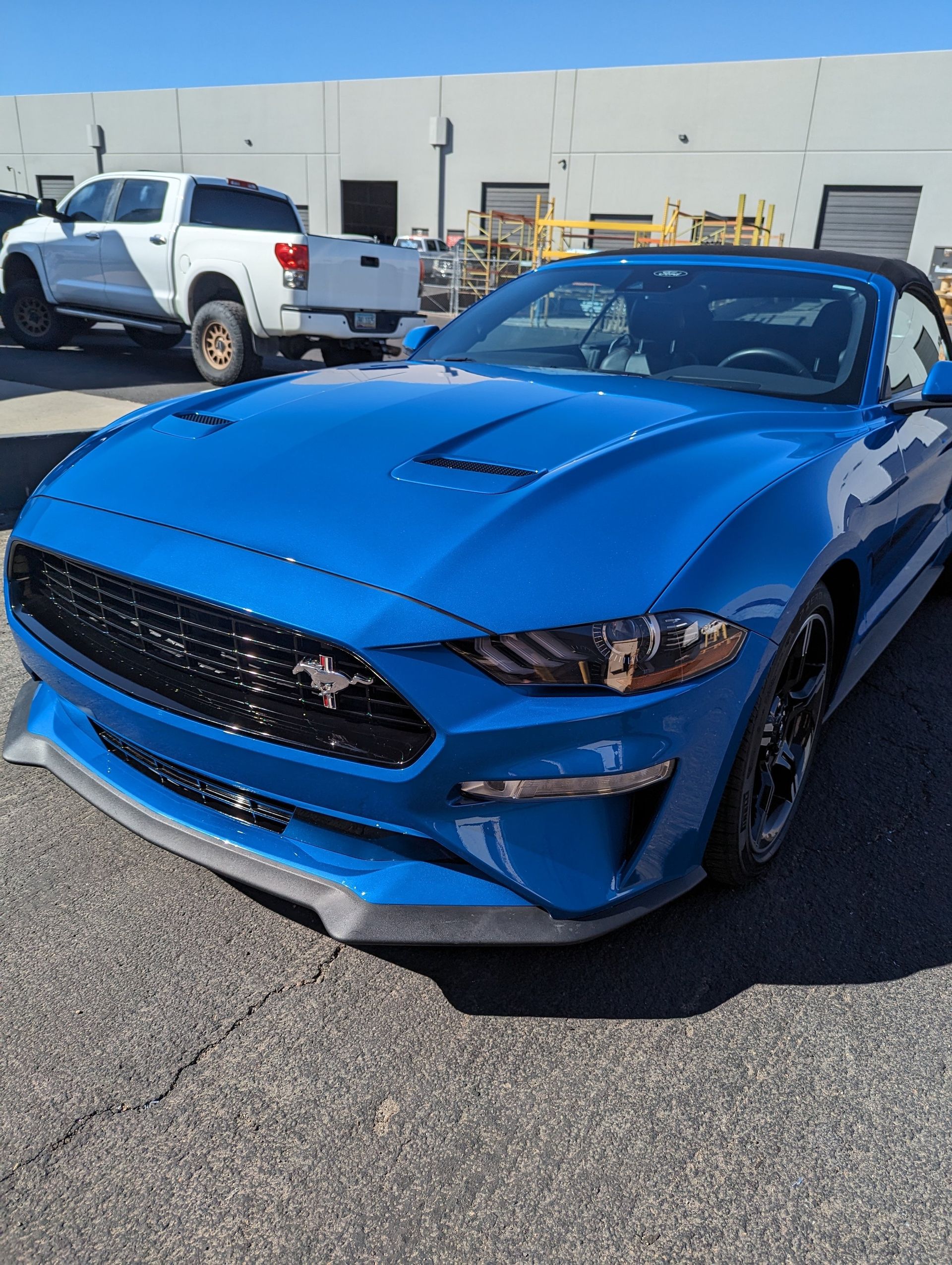 A blue ford mustang is parked in front of a building.