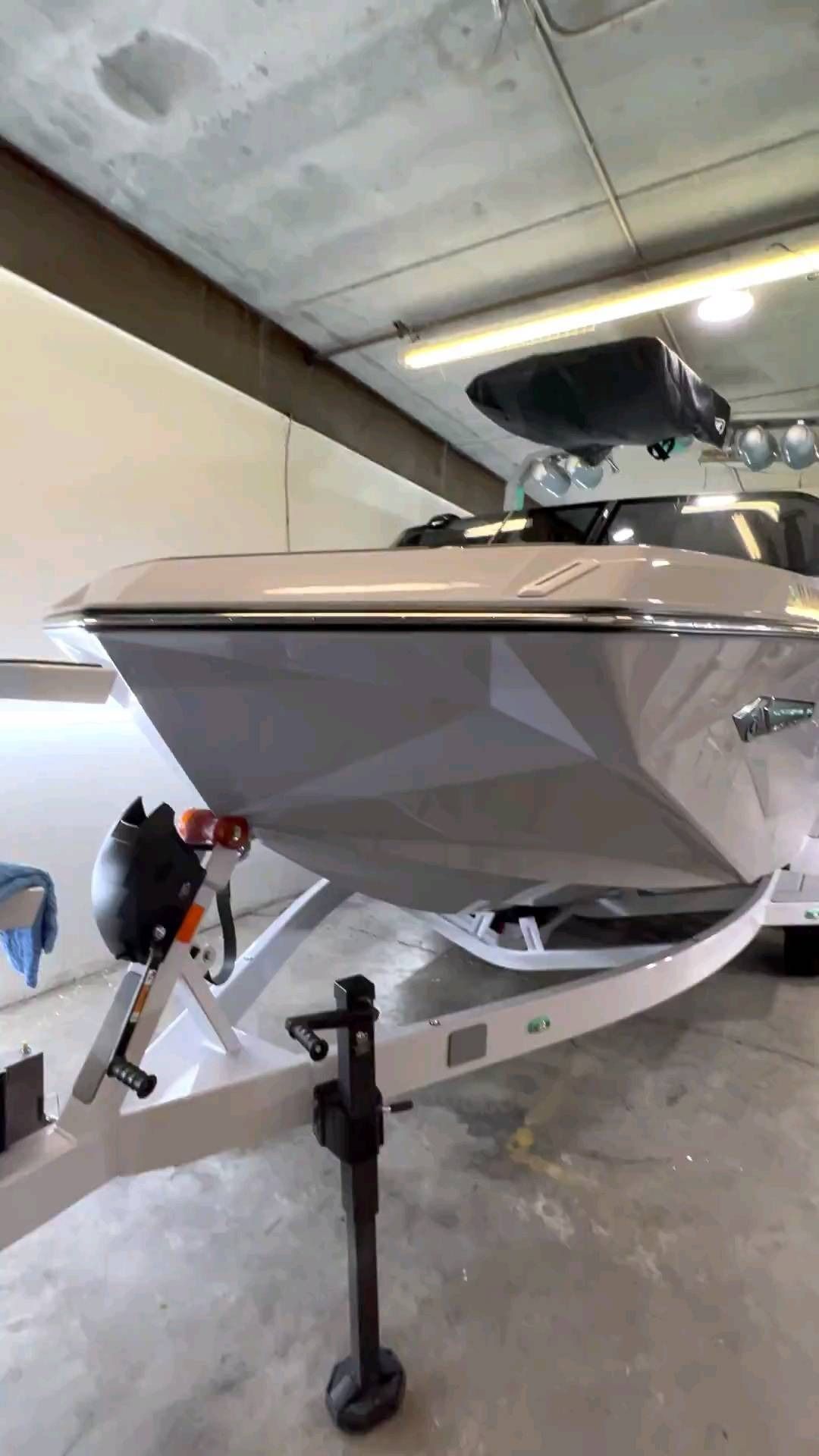 A boat is parked on a trailer in a garage.