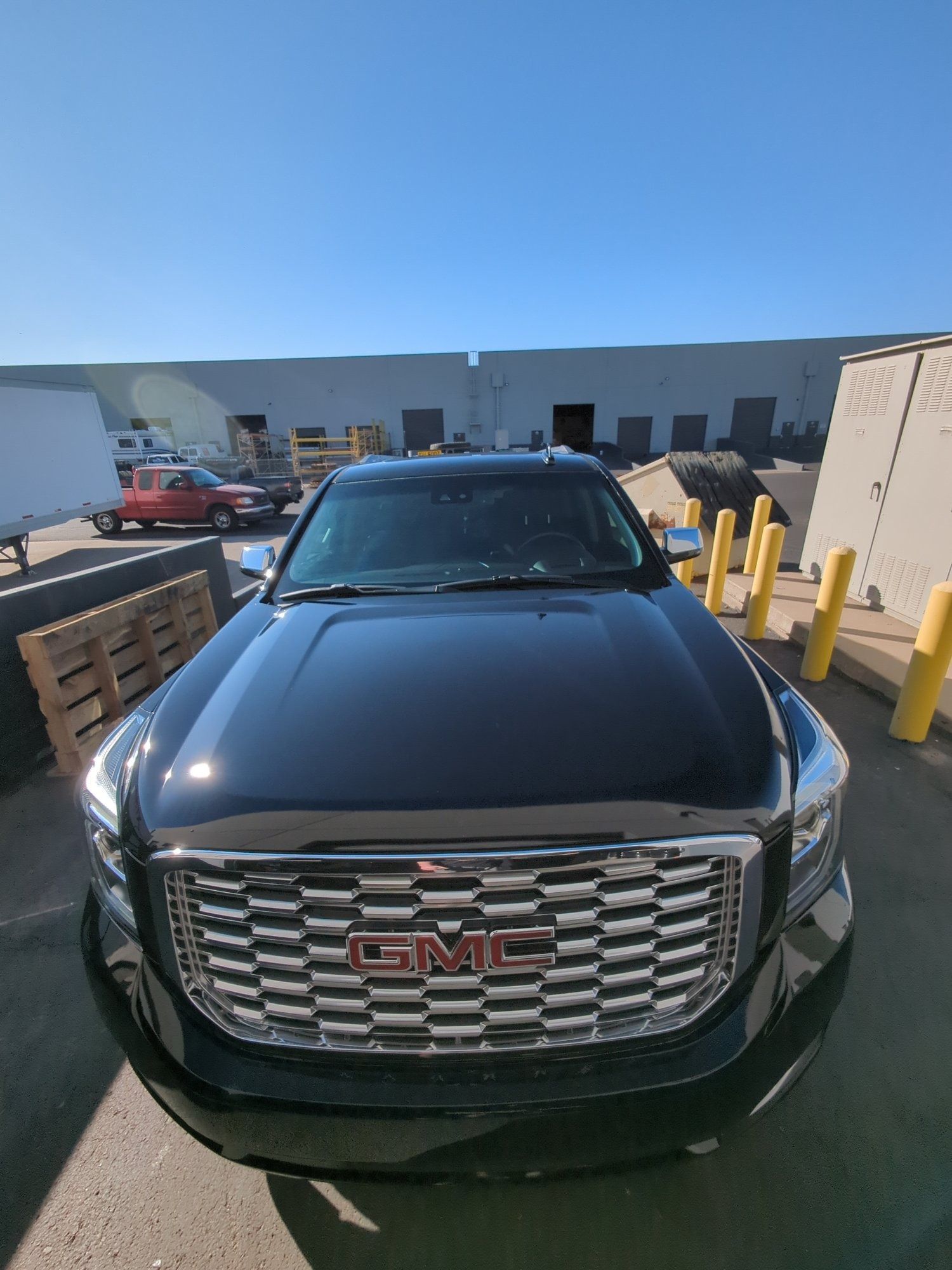 A black gmc truck is parked in front of a building.