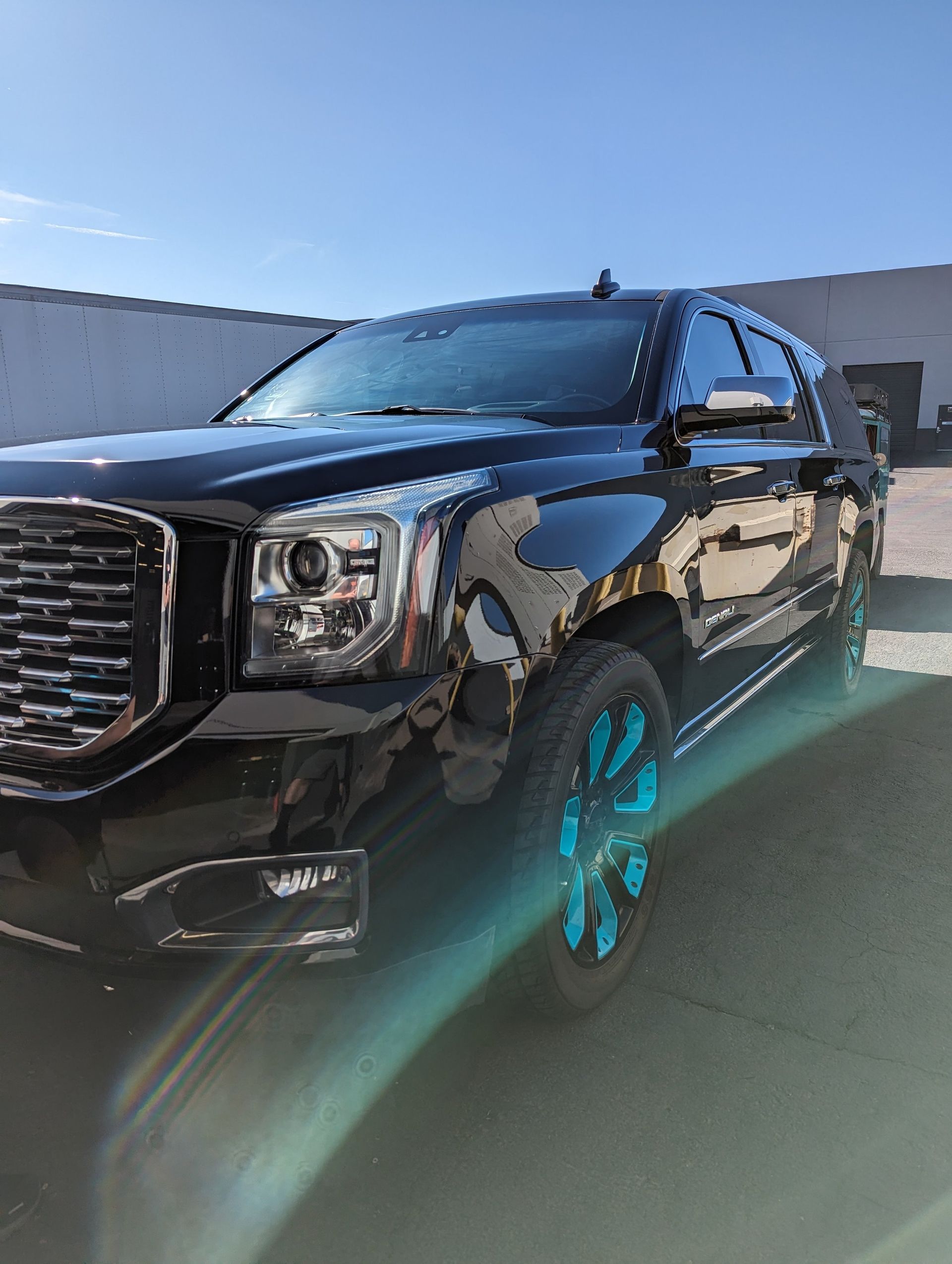 A black suv with blue wheels is parked in front of a building.
