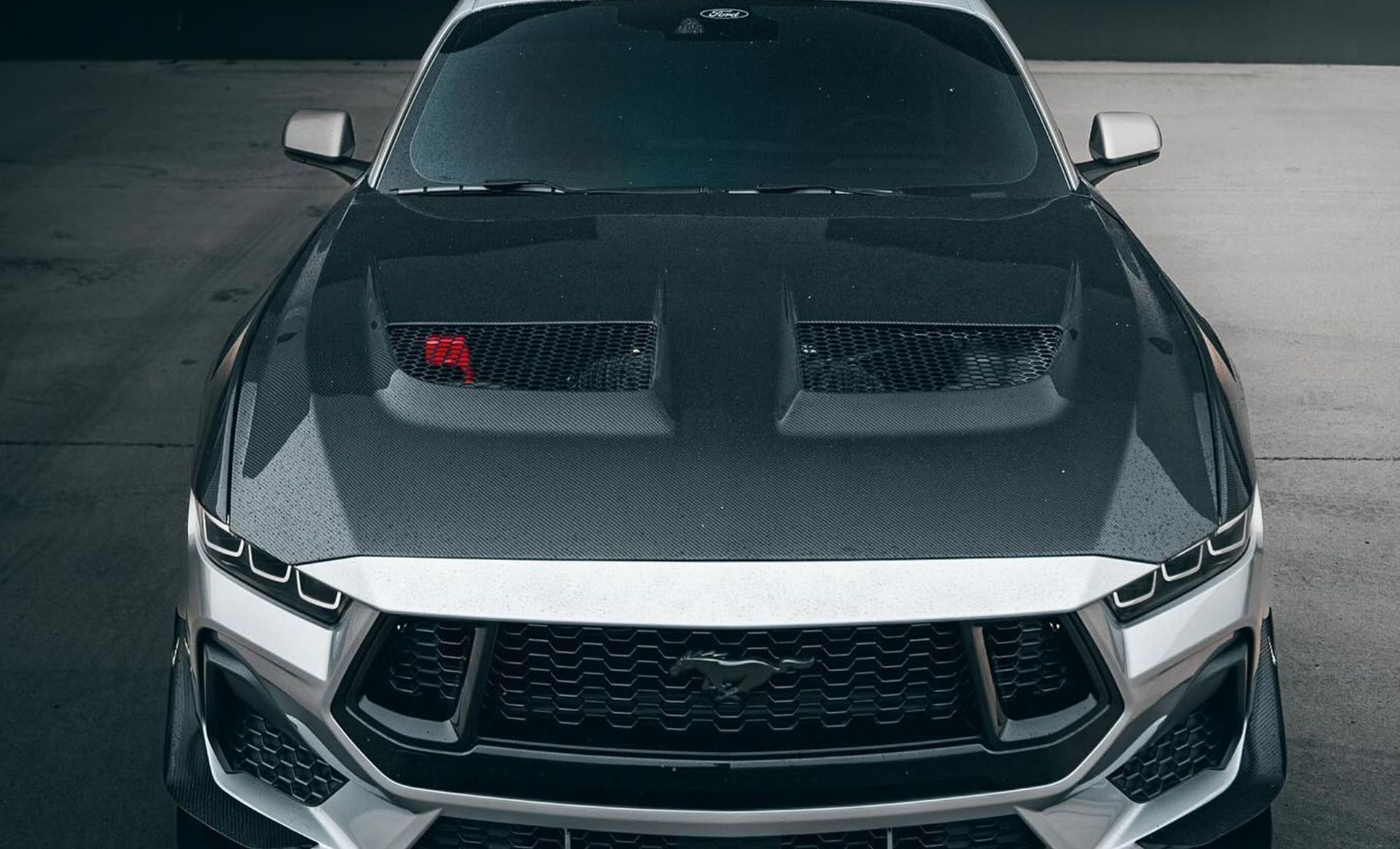 A black and white ford mustang is parked in a garage.