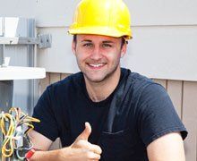 Air conditioning repairman working on a compressor and giving a thumbs-up.