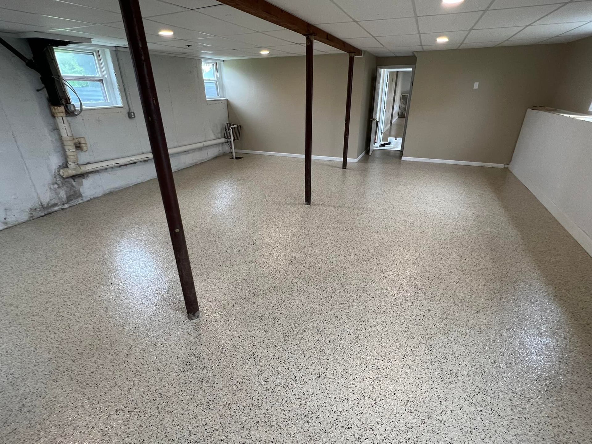 Basement with polished speckled floor, support beams, neutral walls, and recessed lighting.