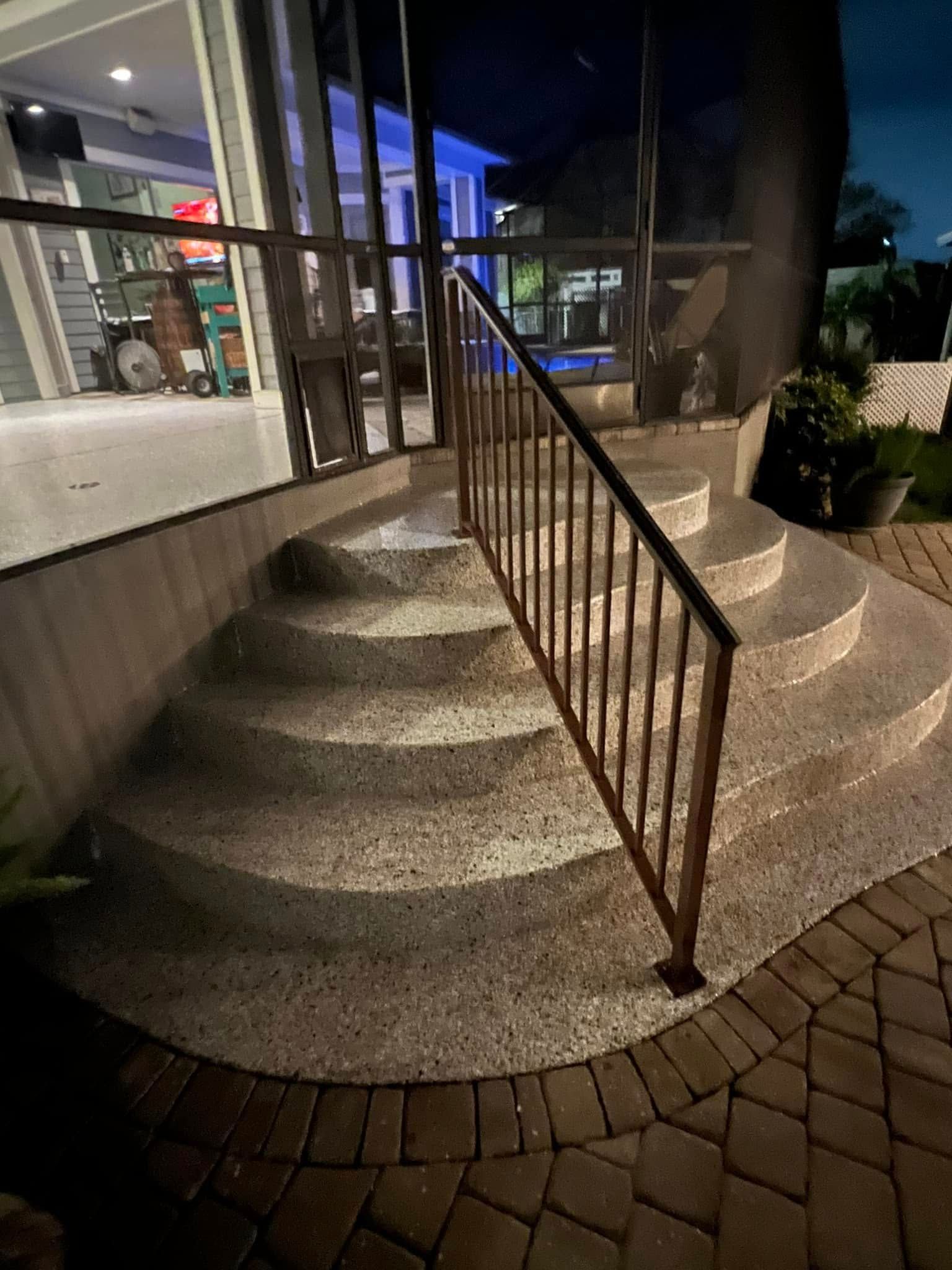 Curved concrete steps with a metal railing leading up to a building at dusk.