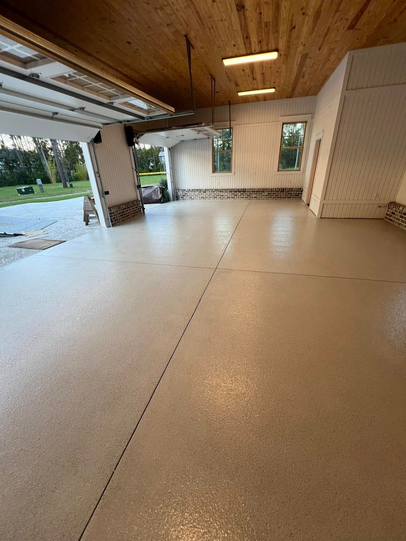 Garage interior with epoxy floor, wood ceiling, and open garage door.