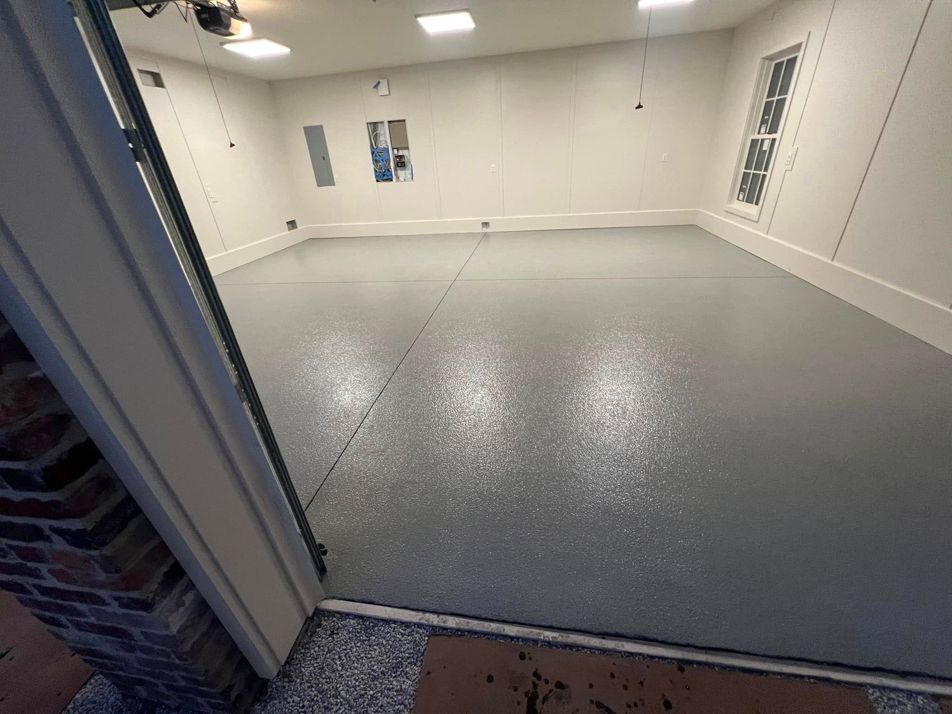 Garage with epoxy floor. Grey, speckled floor. White walls and trim. Viewed from the doorway.
