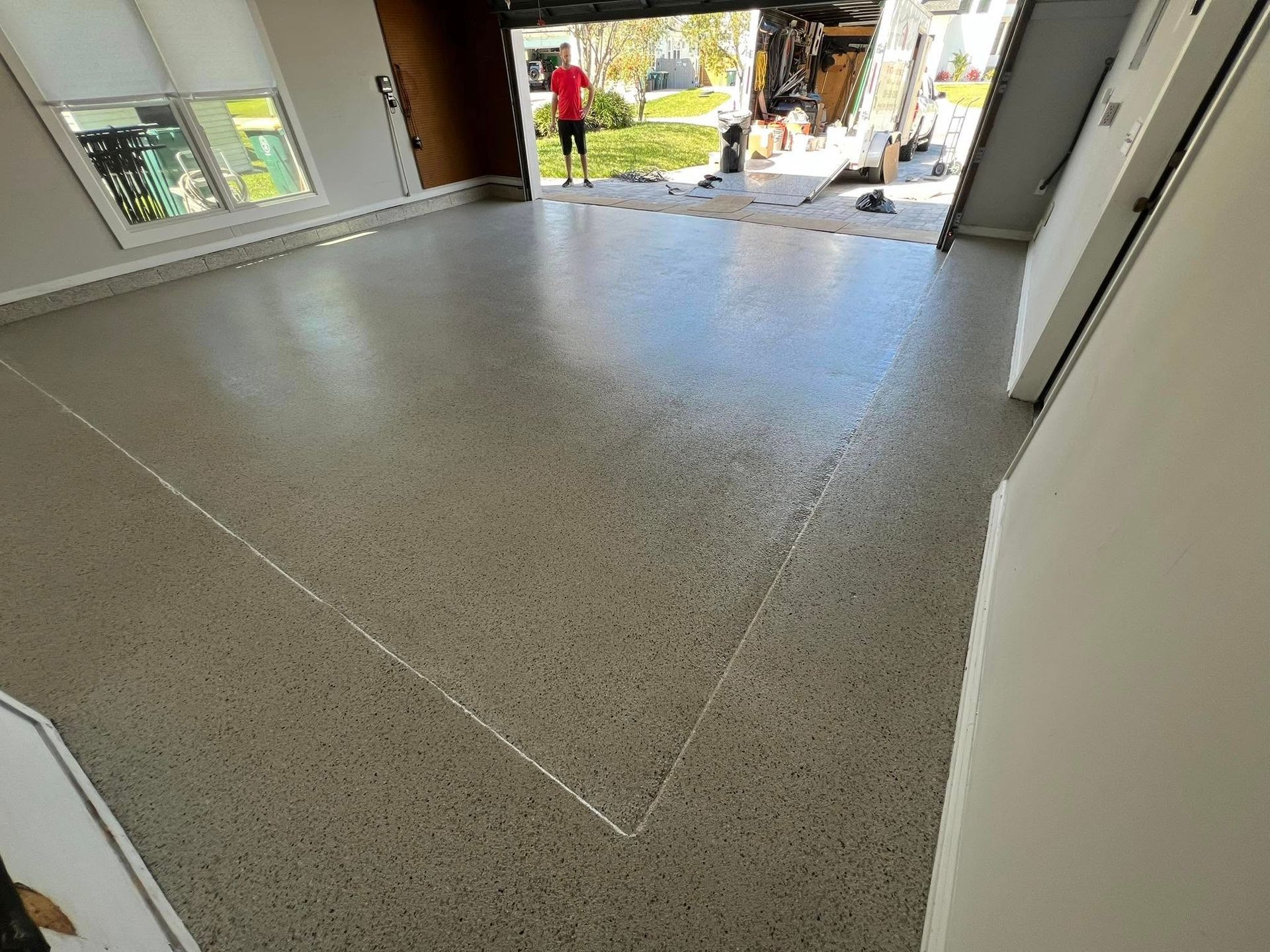 Shiny, speckled garage floor with open door, sunlight, and person.