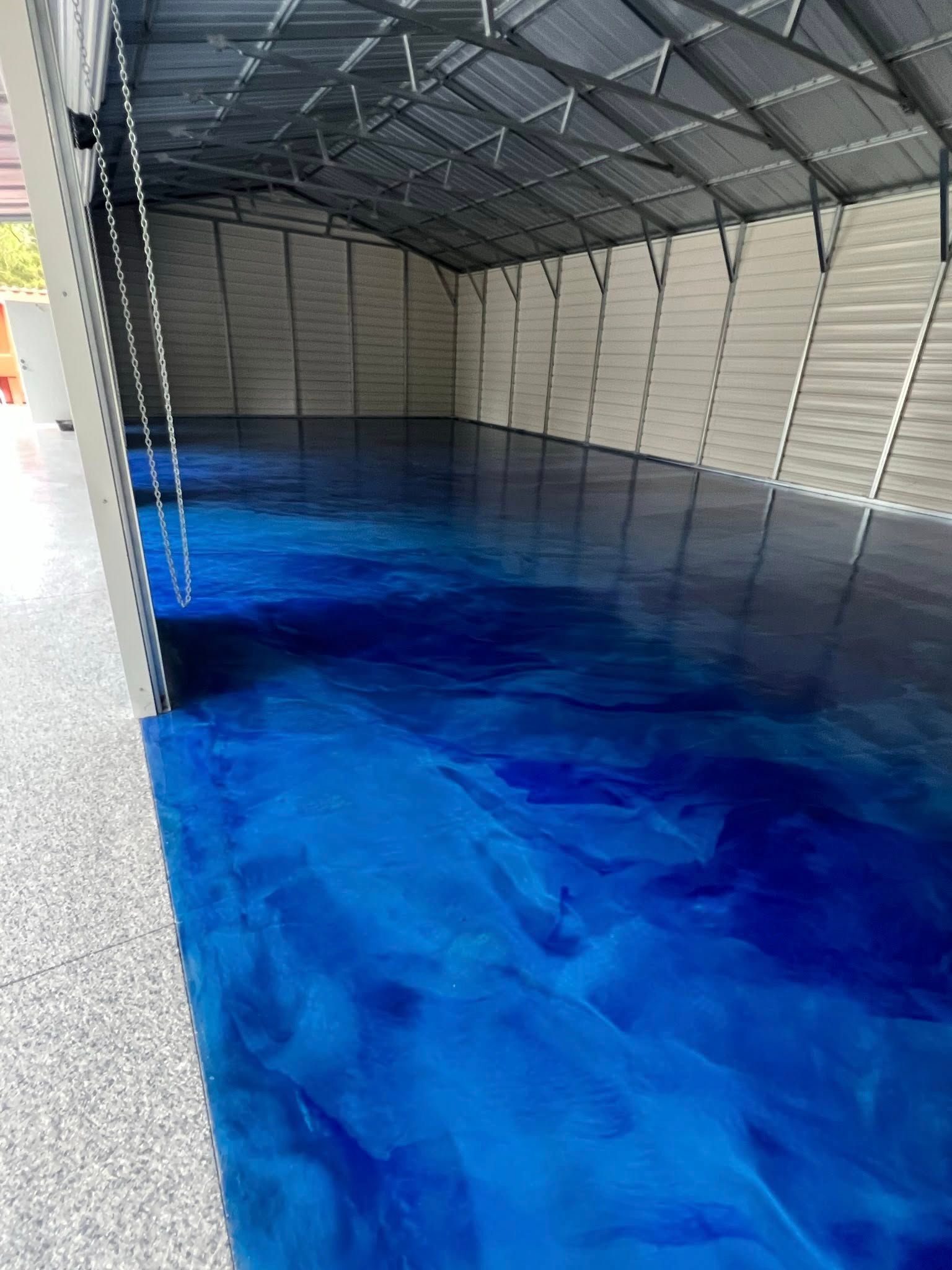 A shed interior with a glossy blue epoxy floor, metal walls, and open door on a light-colored concrete pad.