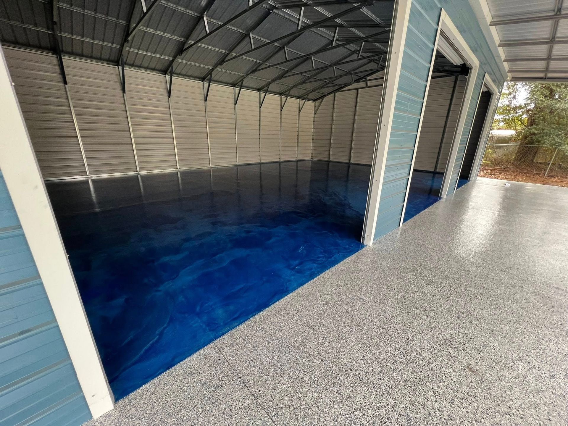 Blue epoxy floor inside open garage bays, light gray concrete outside.