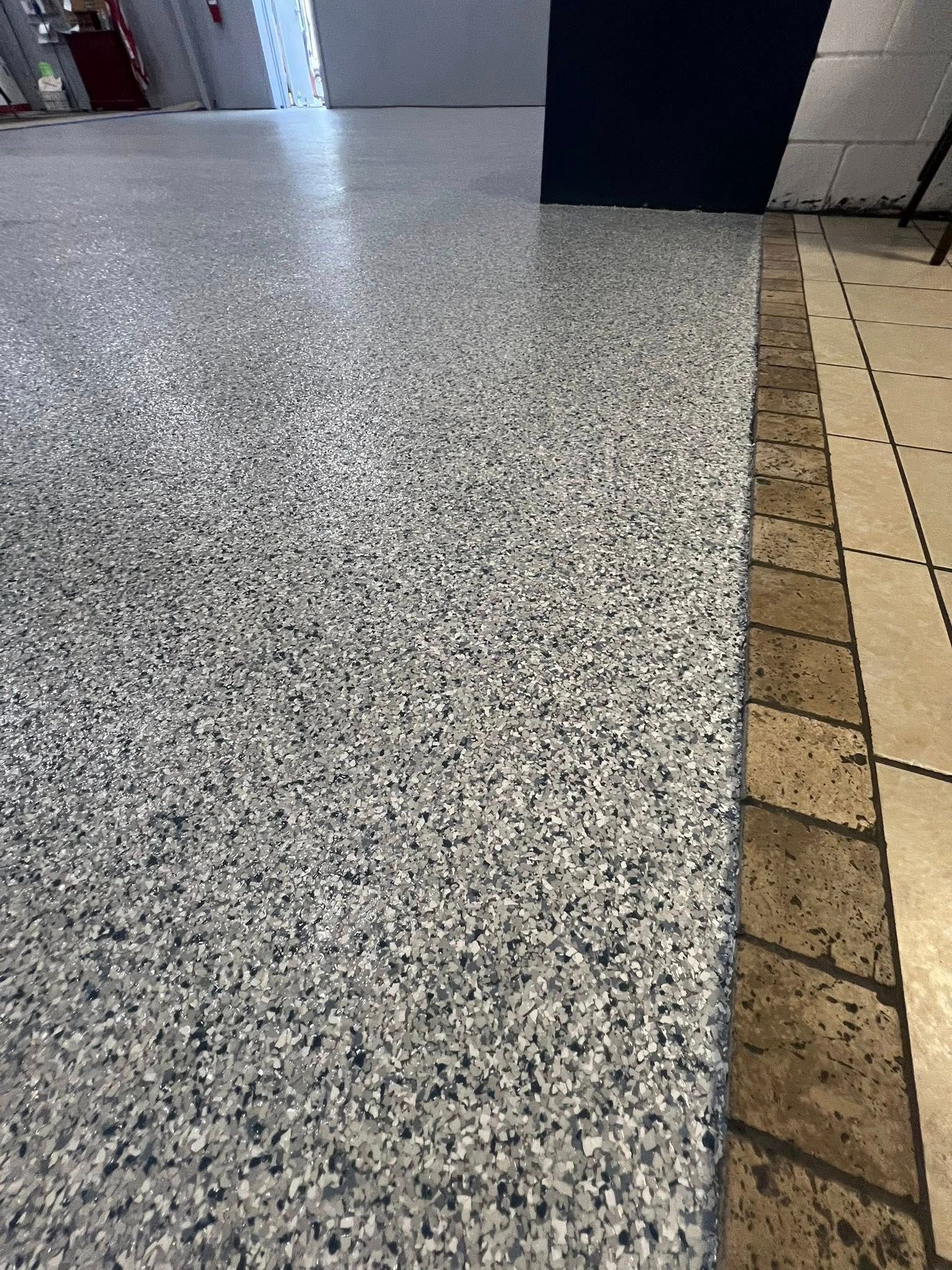 Gray speckled floor transitions to tan tile with a dark brown border.