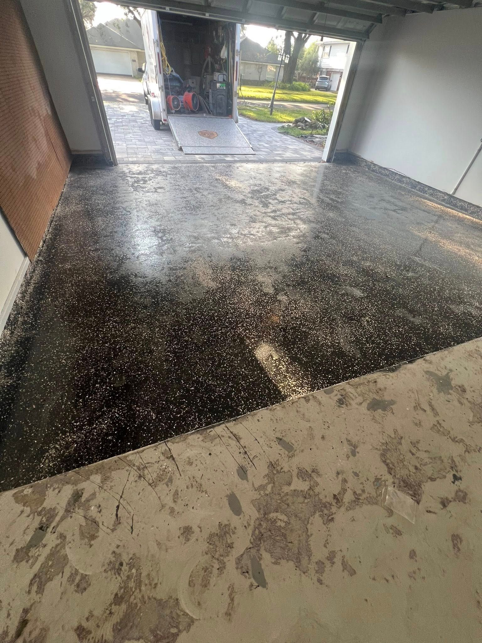 Garage with epoxy floor; moving truck in the opening. Shiny black floor with decorative flecks.