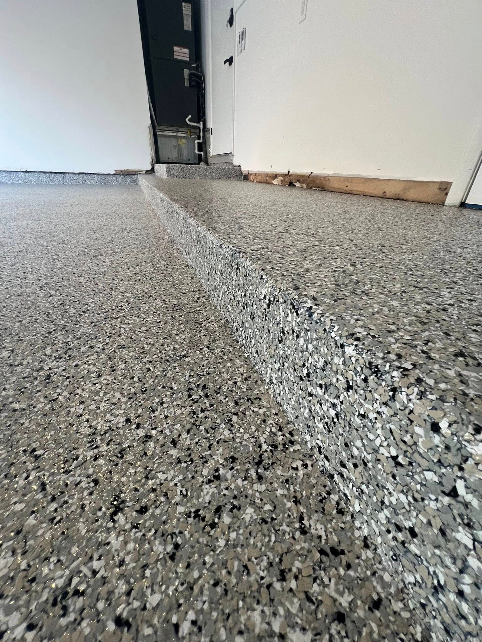 Garage floor with gray and black speckled epoxy coating.