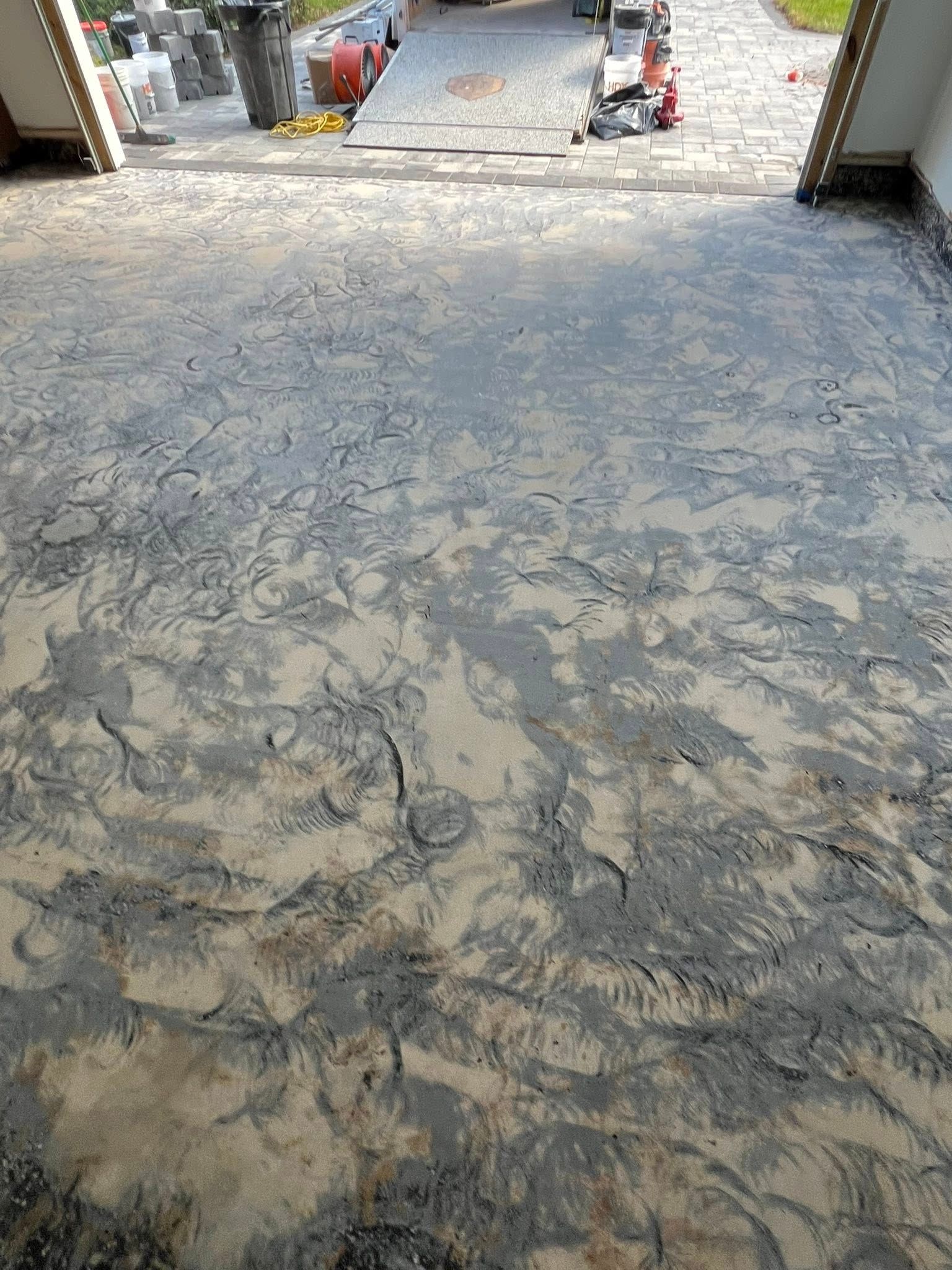 Uneven, textured grey concrete surface in a construction area, leading towards the street.