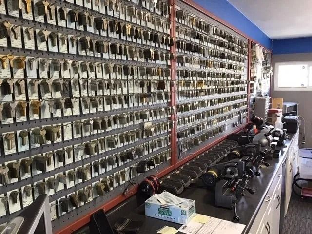 Wall of keys in a locksmith shop with key cutting machines on a counter.