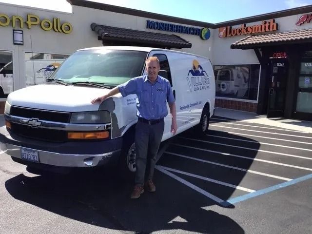 Man stands by a white van in front of a storefront. The van has a company logo on the side.