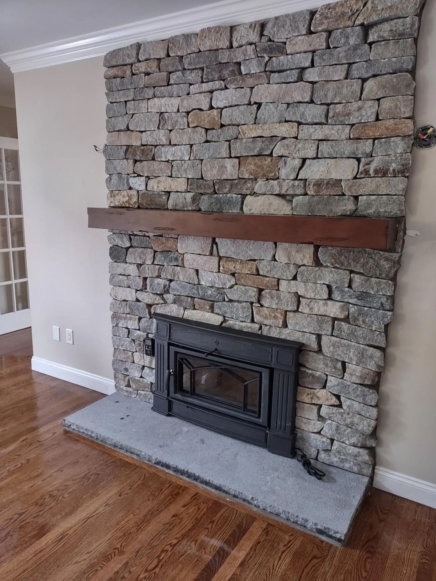 A stone fireplace with a wooden mantle in a living room.