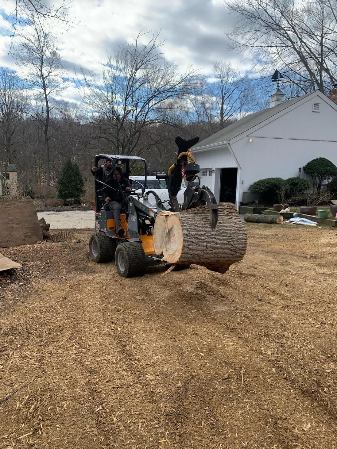 A man is driving a tractor with a large log on it.