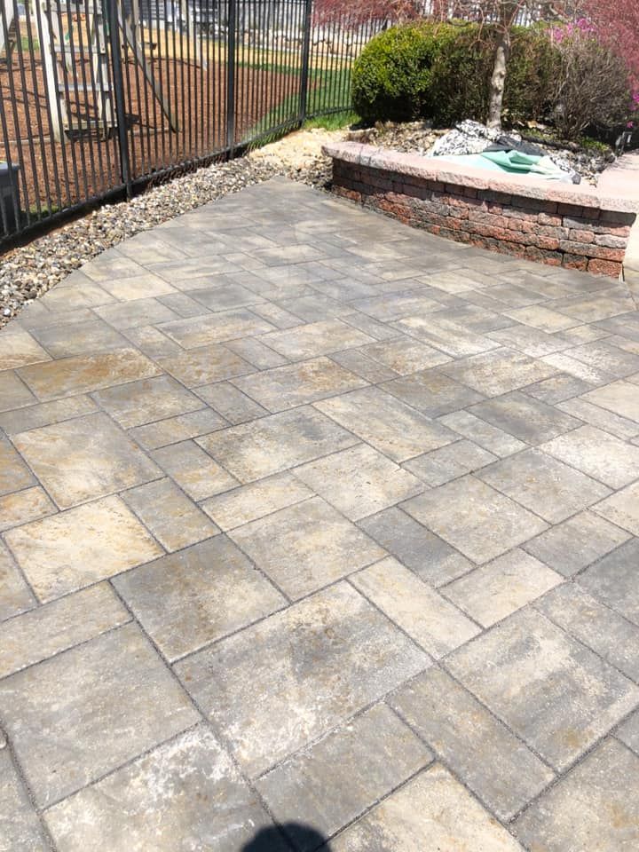 A patio with a fence and a fountain in the background.