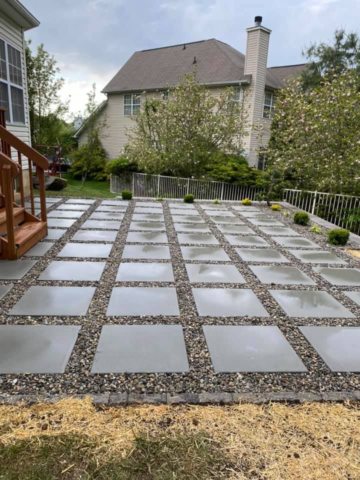 A patio with concrete tiles and gravel in front of a house
