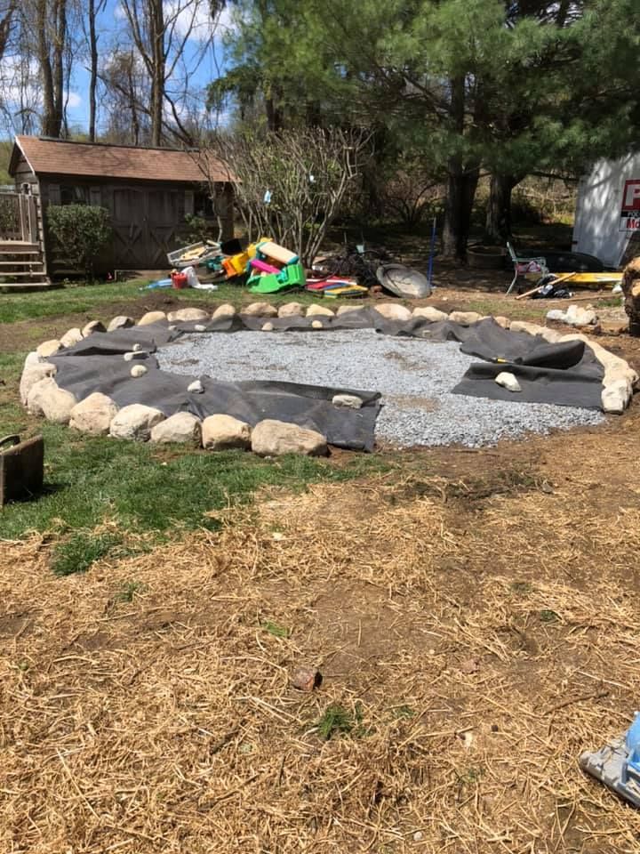 A circle of rocks is being built in a backyard