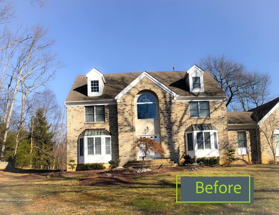 A large brick house with a brown roof is sitting on top of a lush green field.
