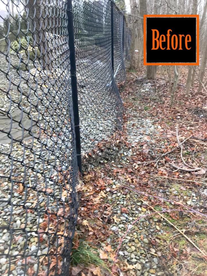 A chain link fence is surrounded by rocks and leaves