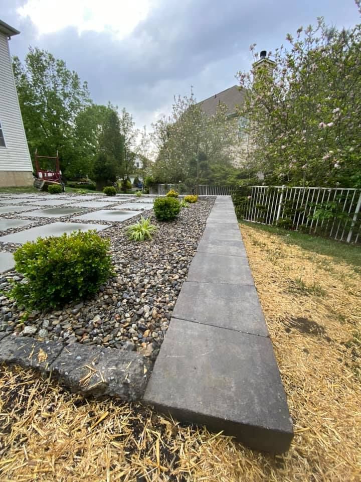 A walkway leading to a house with a fence in the background