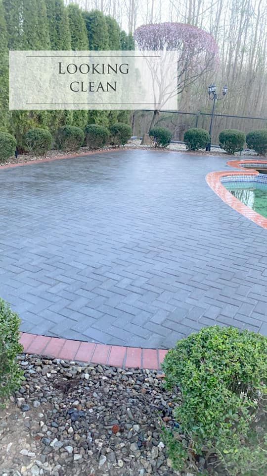 A brick driveway with a pool in the background 