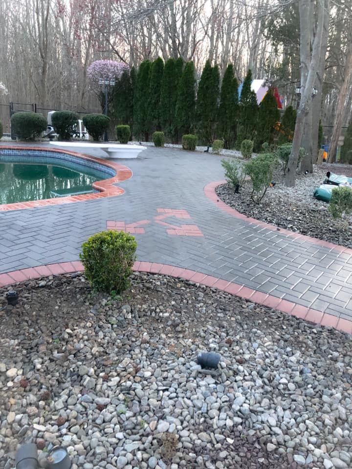 A brick walkway leading to a pool in a backyard
