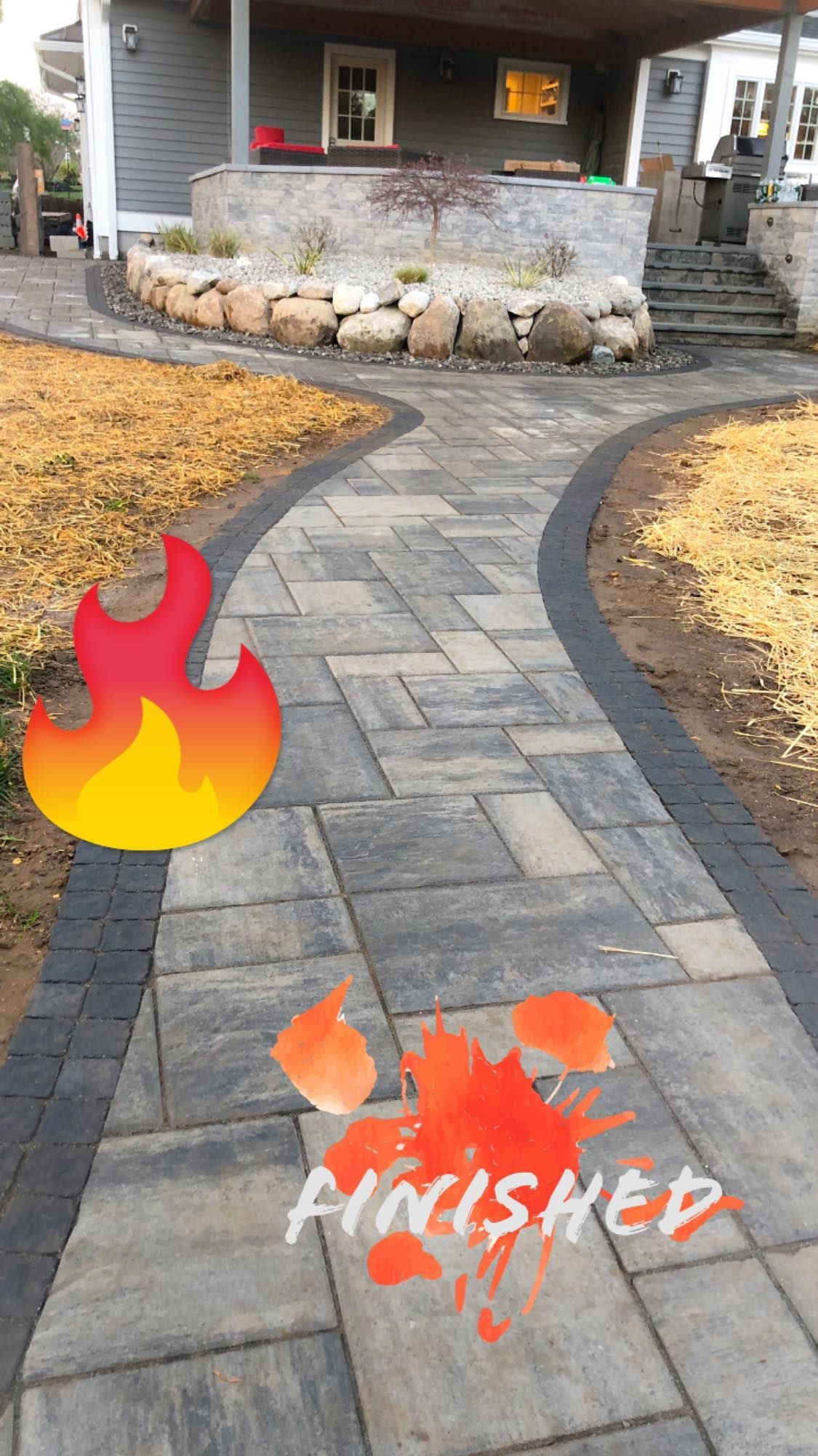 A brick walkway is being finished in front of a house