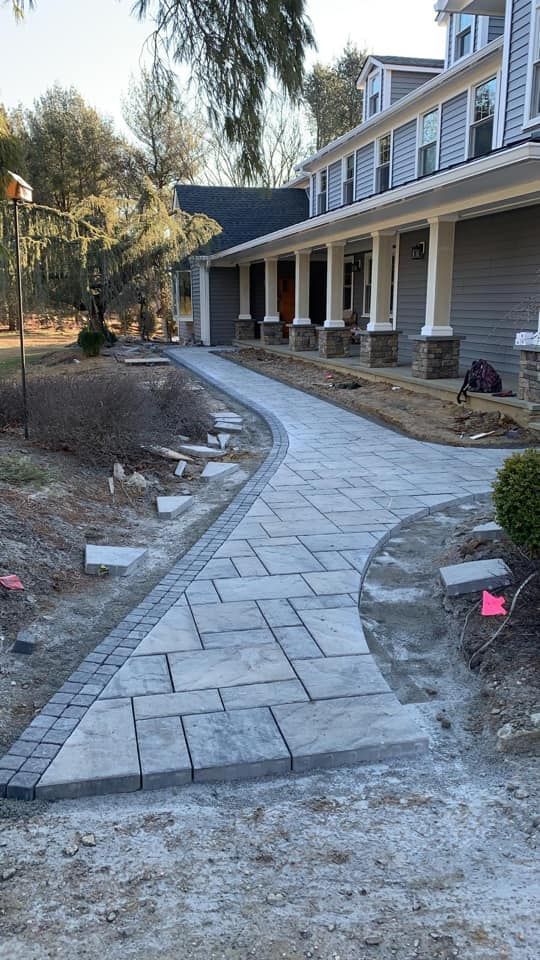 A concrete walkway is being built in front of a large house.